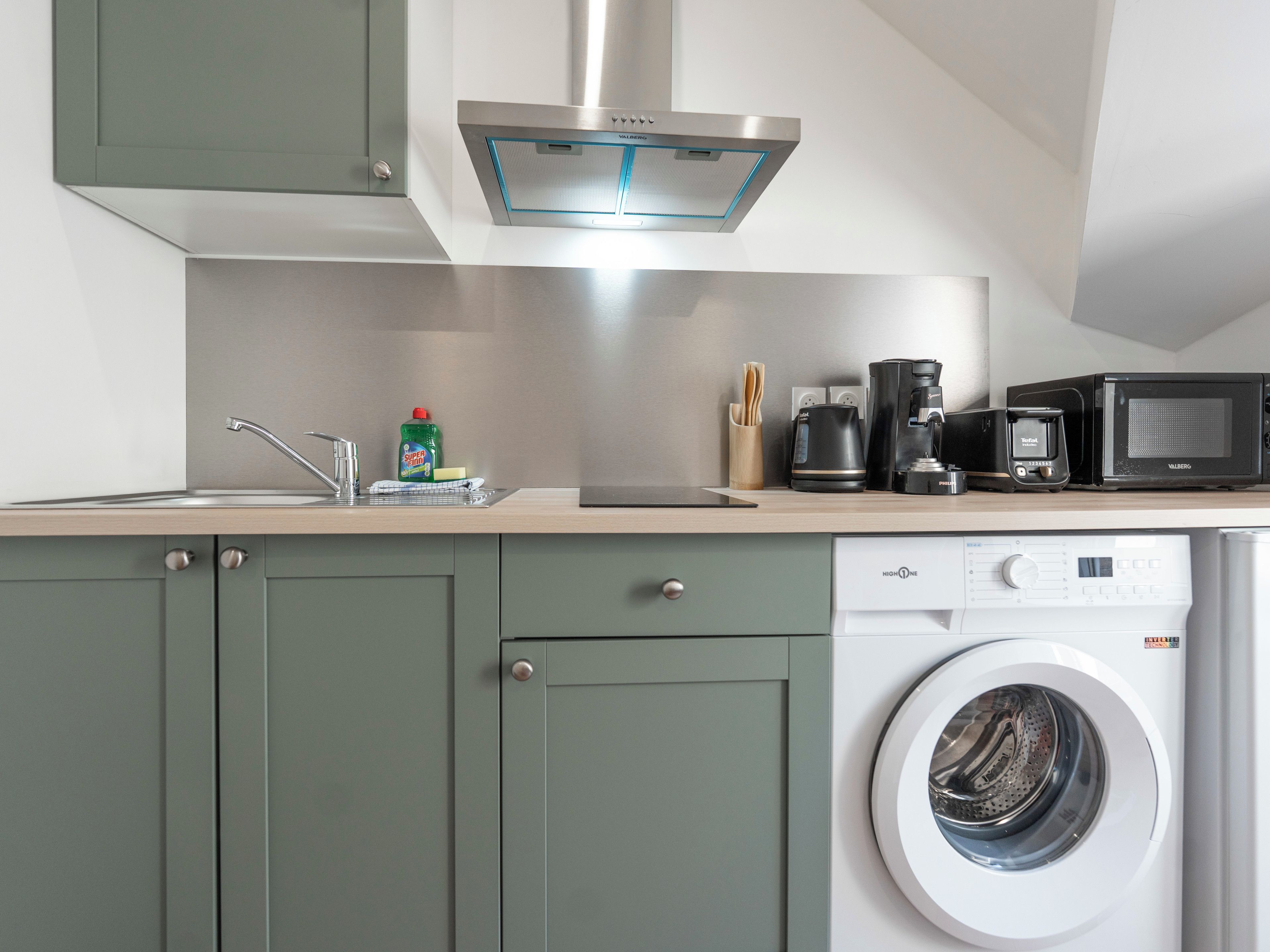 A modern kitchen with a built-in washing machine, a coffee maker, and a microwave.