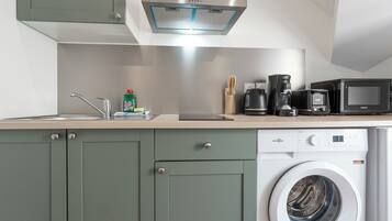 A modern kitchen with a built-in washing machine, a coffee maker, and a microwave.