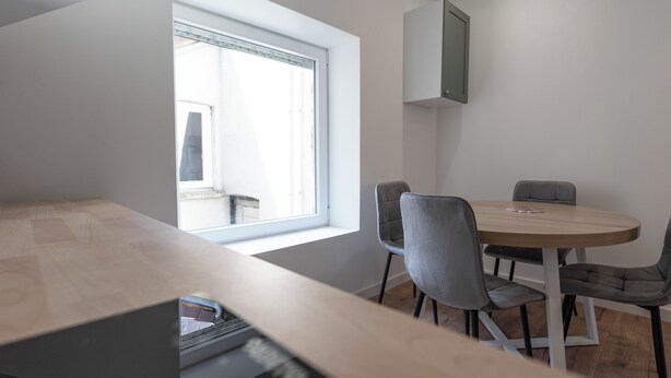 A modern dining area with a round table, four chairs, and a window providing natural light. - #IR | L'Amiral 41 💟 - Grenoble (Grenoble)