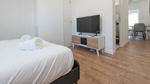 A modern hotel room with a bed, a flat-screen TV, a wooden floor, and a desk with a chair. - #IR | L'Amiral 41 💟 - Grenoble (Grenoble)