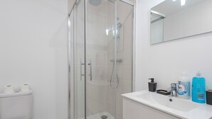 A bathroom with a glass-enclosed shower, a toilet, and a vanity with toiletries. - #IR | L'Amiral 41 💟 - Grenoble (Grenoble)