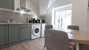 A modern kitchen with a built-in washing machine, a dining area with a table and chairs, and a window providing natural light. - #IR | L'Amiral 41 💟 - Grenoble (Grenoble)