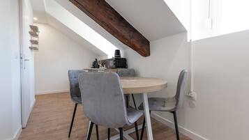 A dining area with a round table, four chairs, and a wooden beam ceiling.