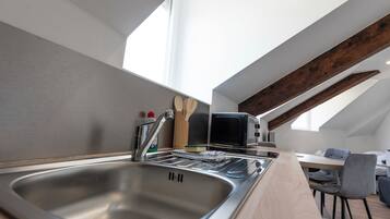 A modern kitchen with a stainless steel sink, a microwave, and wooden utensils on the counter.