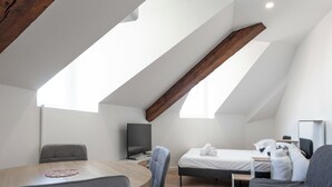 A modern, well-lit room with a sloped ceiling, a bed, a desk, and a television. - #IS | L'Amiral 42 💟 - Grenoble (Grenoble)