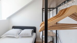 Un dormitorio con una cama, un perchero de madera y una ventana.