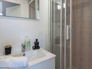 A bathroom with a white sink, a mirror, a glass shower enclosure, and a towel on the floor. - #IT | L'Amiral 43 💟 - Grenoble (Grenoble)