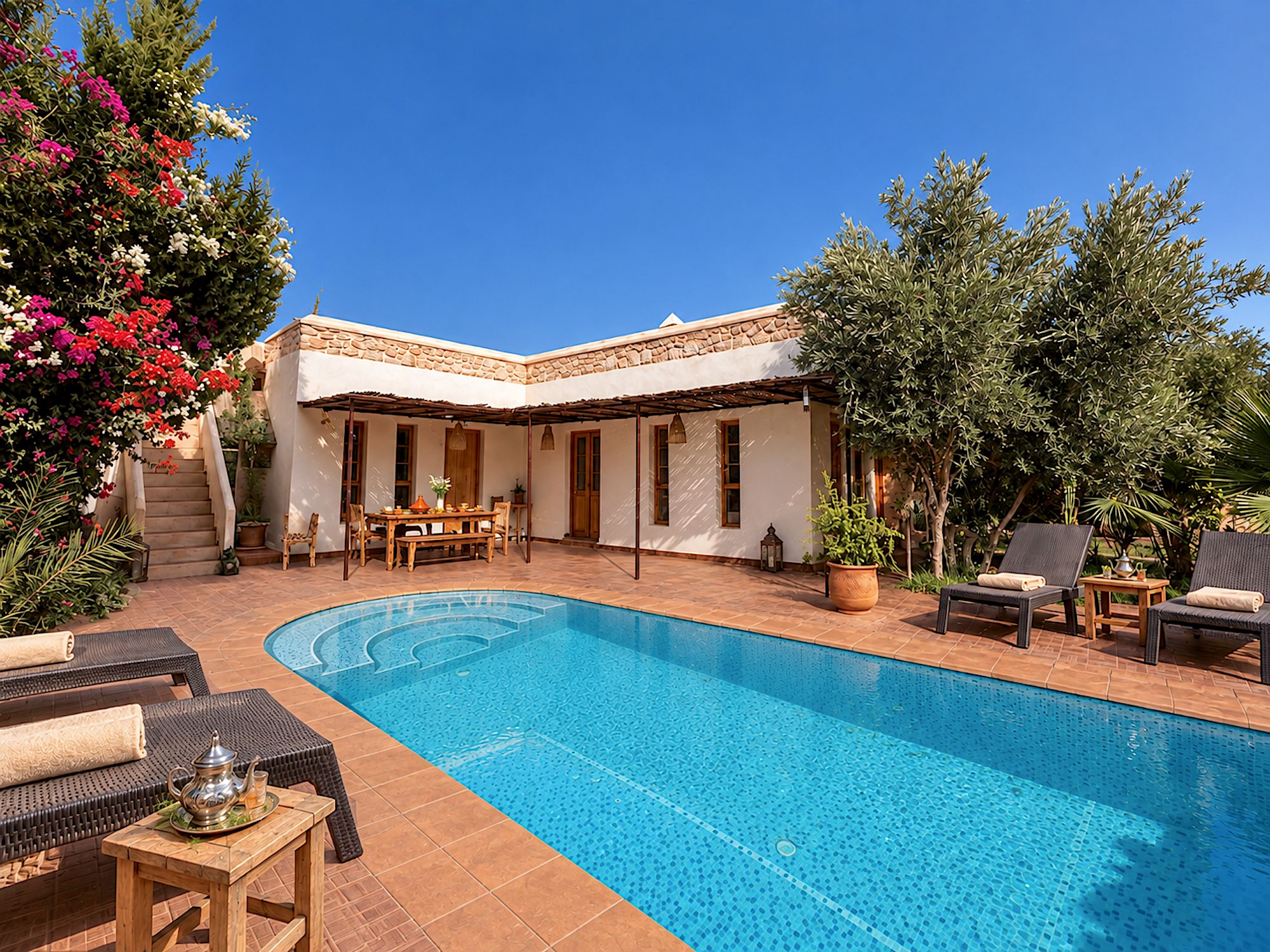 Ein Poolbereich mit Pool, Gartenmöbeln und einem Gebäude mit Steinfassade.