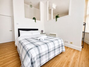 A bedroom with a bed, a nightstand, a lamp, and a window with blinds. - Fantastic 1BDR Studio in the Heart of City Centre (Liverpool)