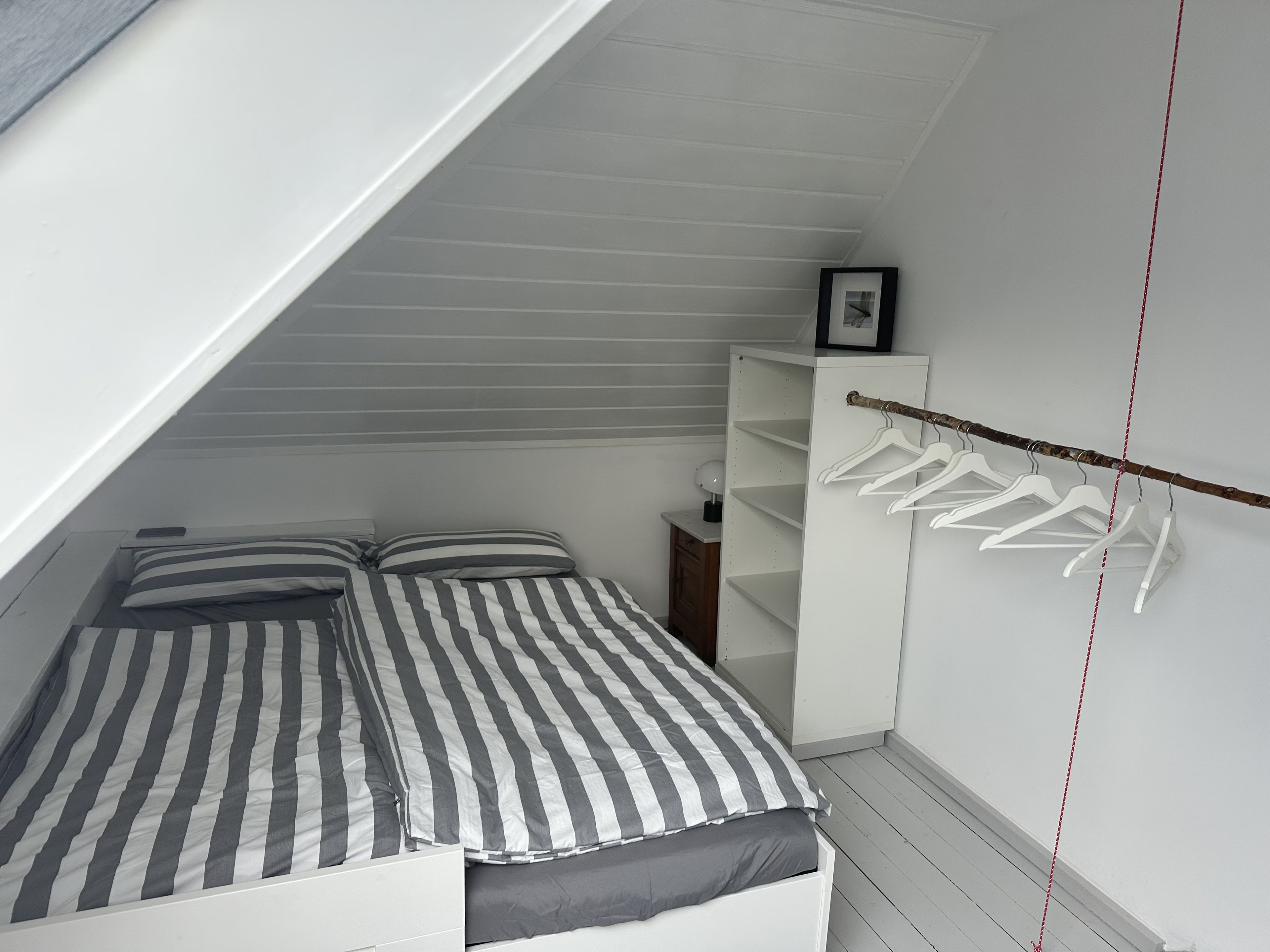 Un dormitorio con una cama, un armario y una percha.