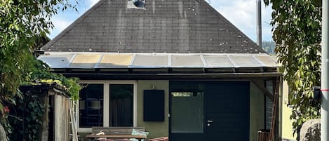 A building with a sloped roof, a covered porch, and a garage door.