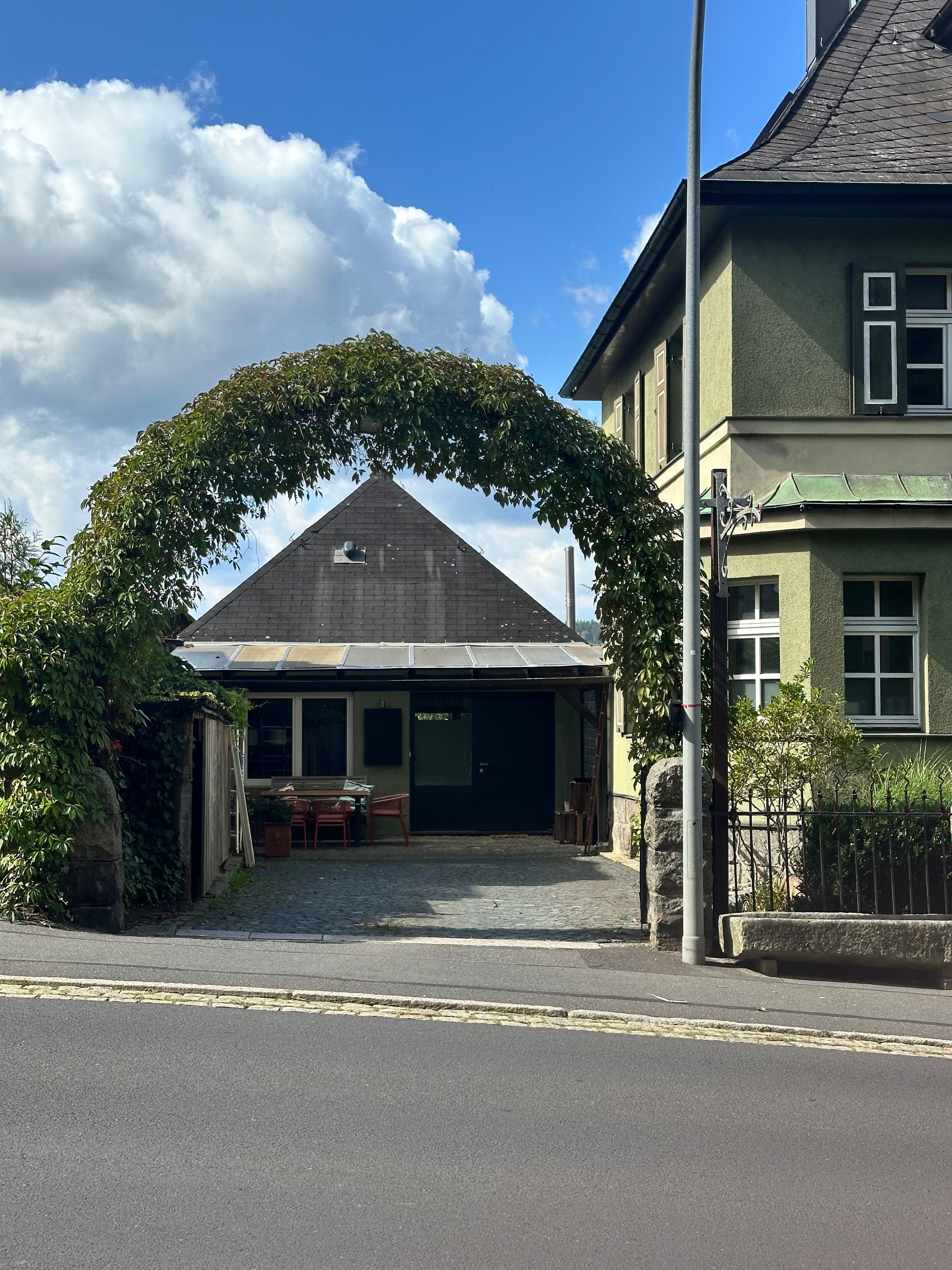 Een gebouw met een overdekte entree, een zichtbare garagepoort en een verharde oprit.