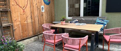 An outdoor patio with a wooden table, wicker chairs, and a bench.