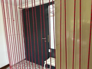 A room with a patterned floor, a door with a red and black striped curtain, and a small white table.