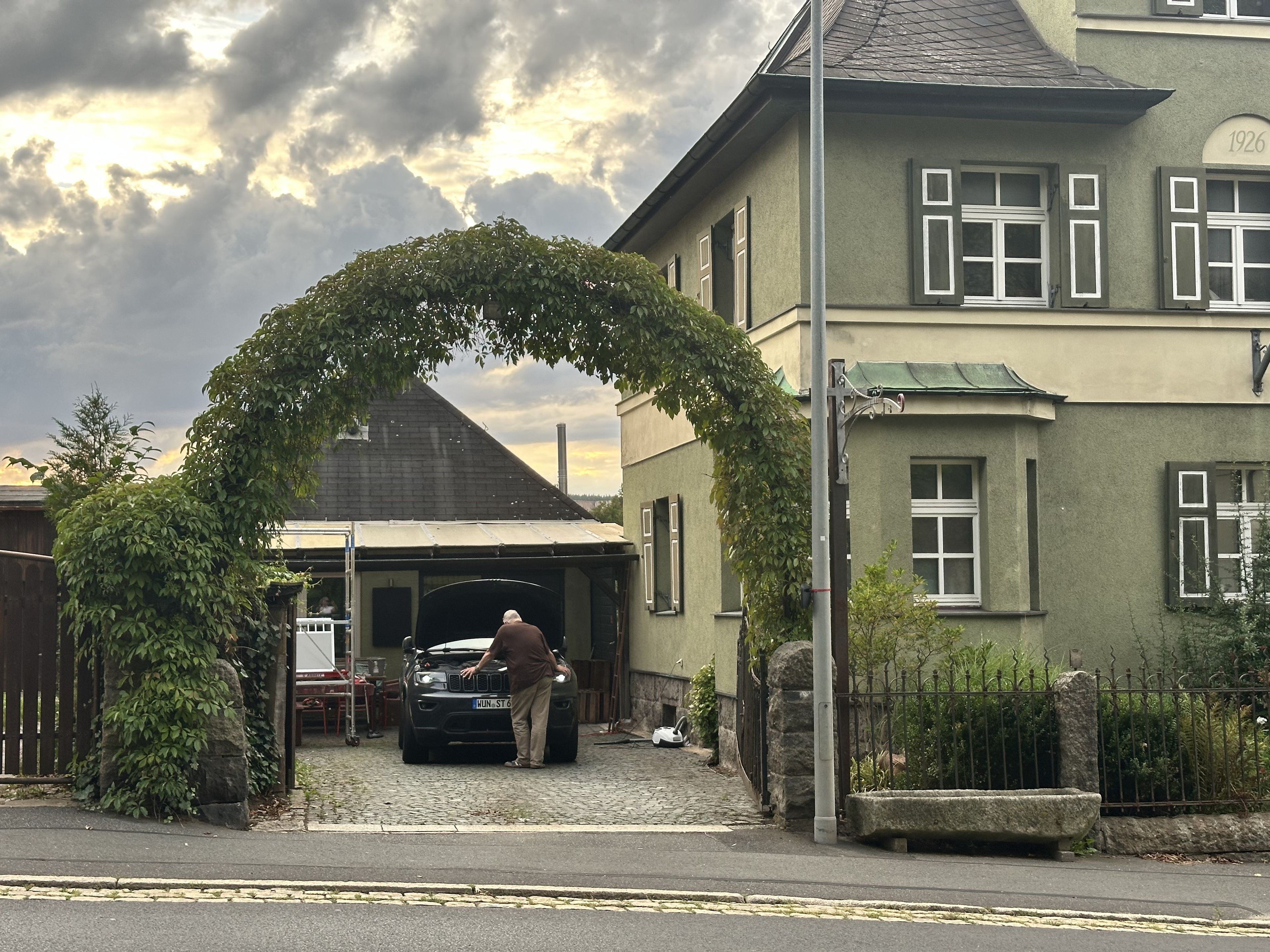 A residential building with a garage entrance, a stone wall, and a metal fence.