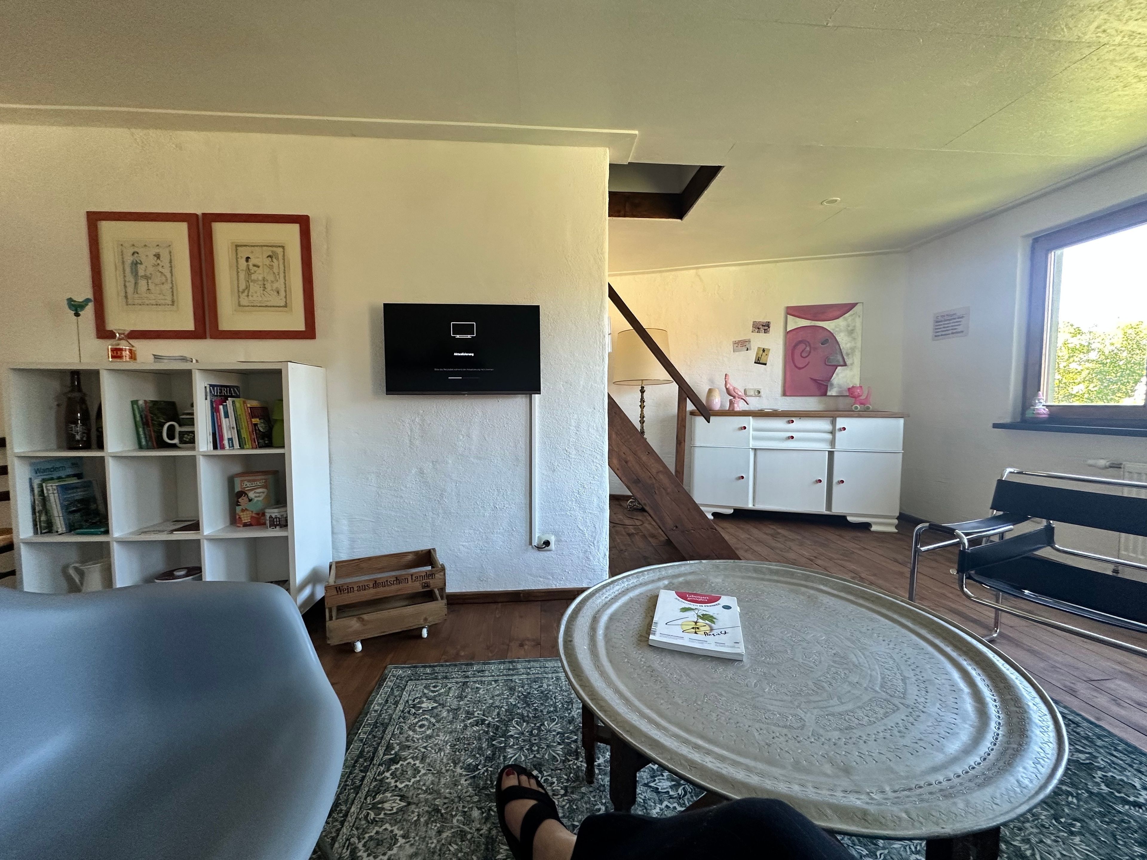 Un salon équipé d’un téléviseur, de bibliothèques, d’une table basse et d’un escalier menant à une autre pièce.