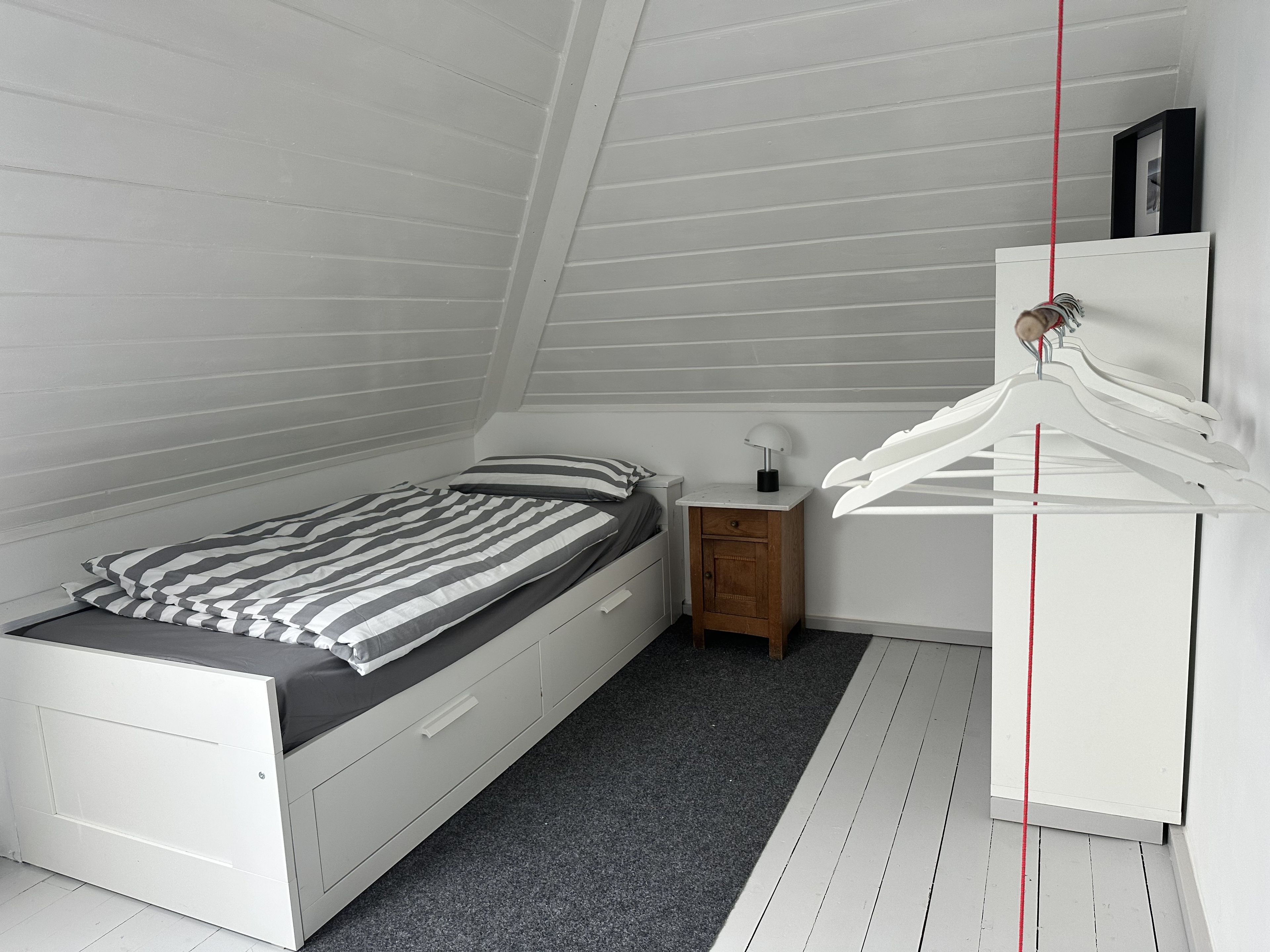 Ein Schlafzimmer mit einem Bett, einem Nachttisch, einer Kommode und einer Pendelleuchte.