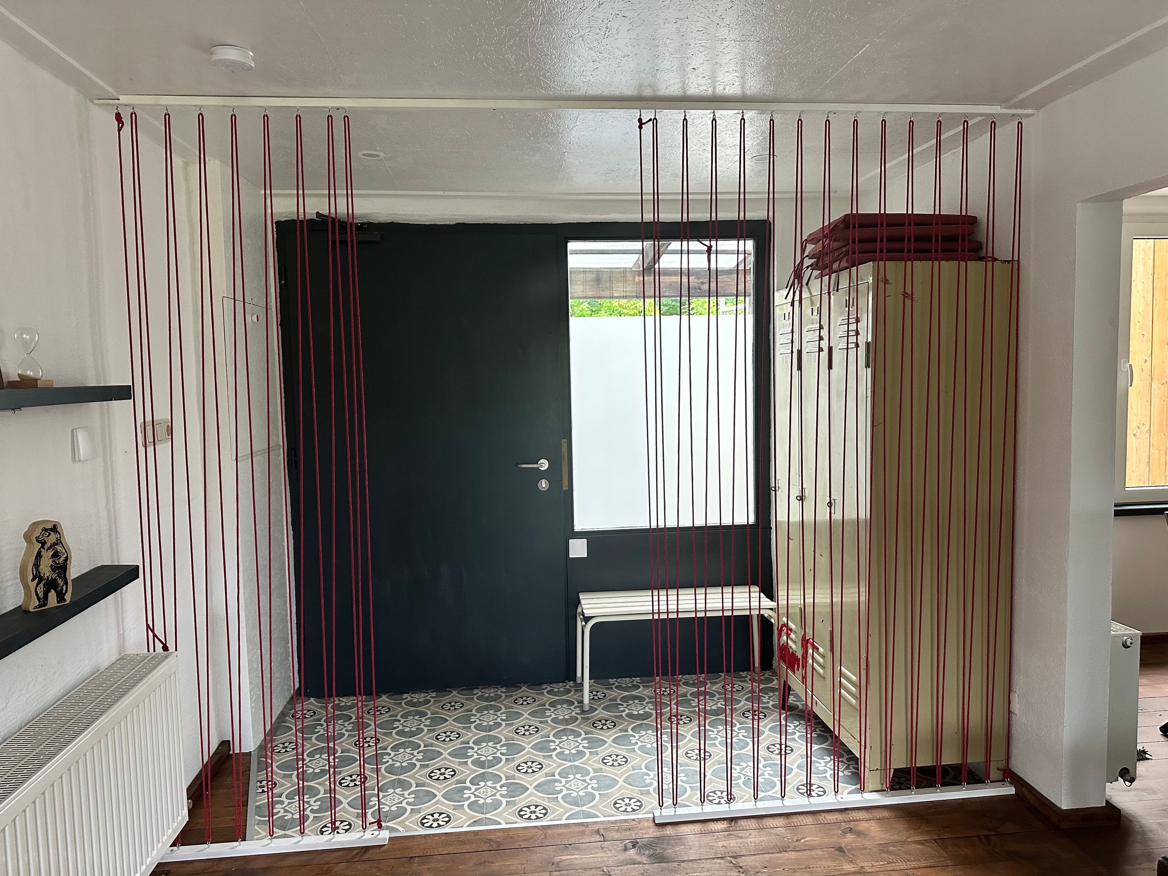 Une pièce avec une porte sombre, une fenêtre, un radiateur et un sol à motifs.
