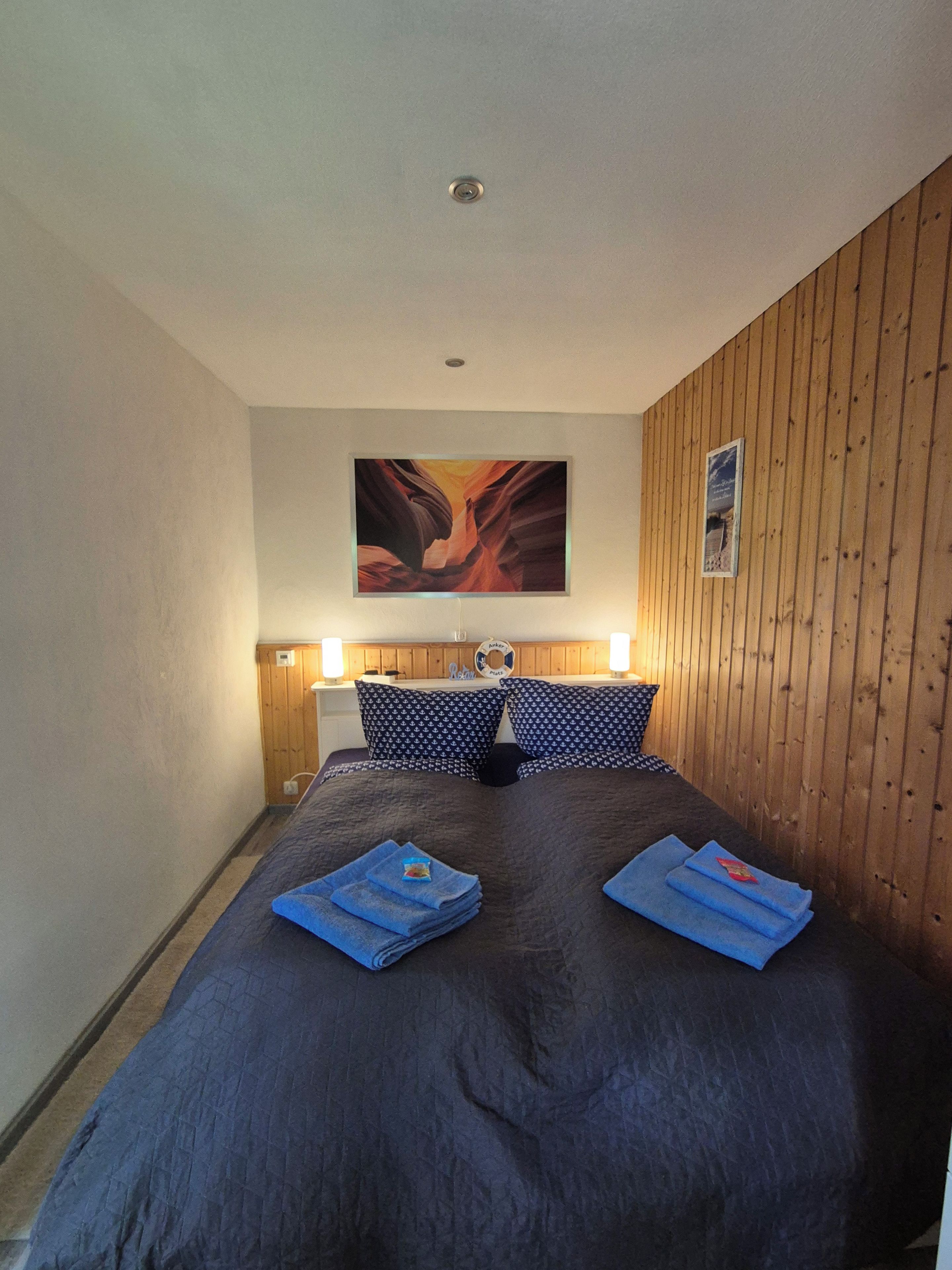 A hotel room with a large bed, two bedside lamps, a wooden headboard, and a painting on the wall.