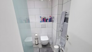 Et moderne badeværelse med toilet, bidet og et håndklædetørrestativ.