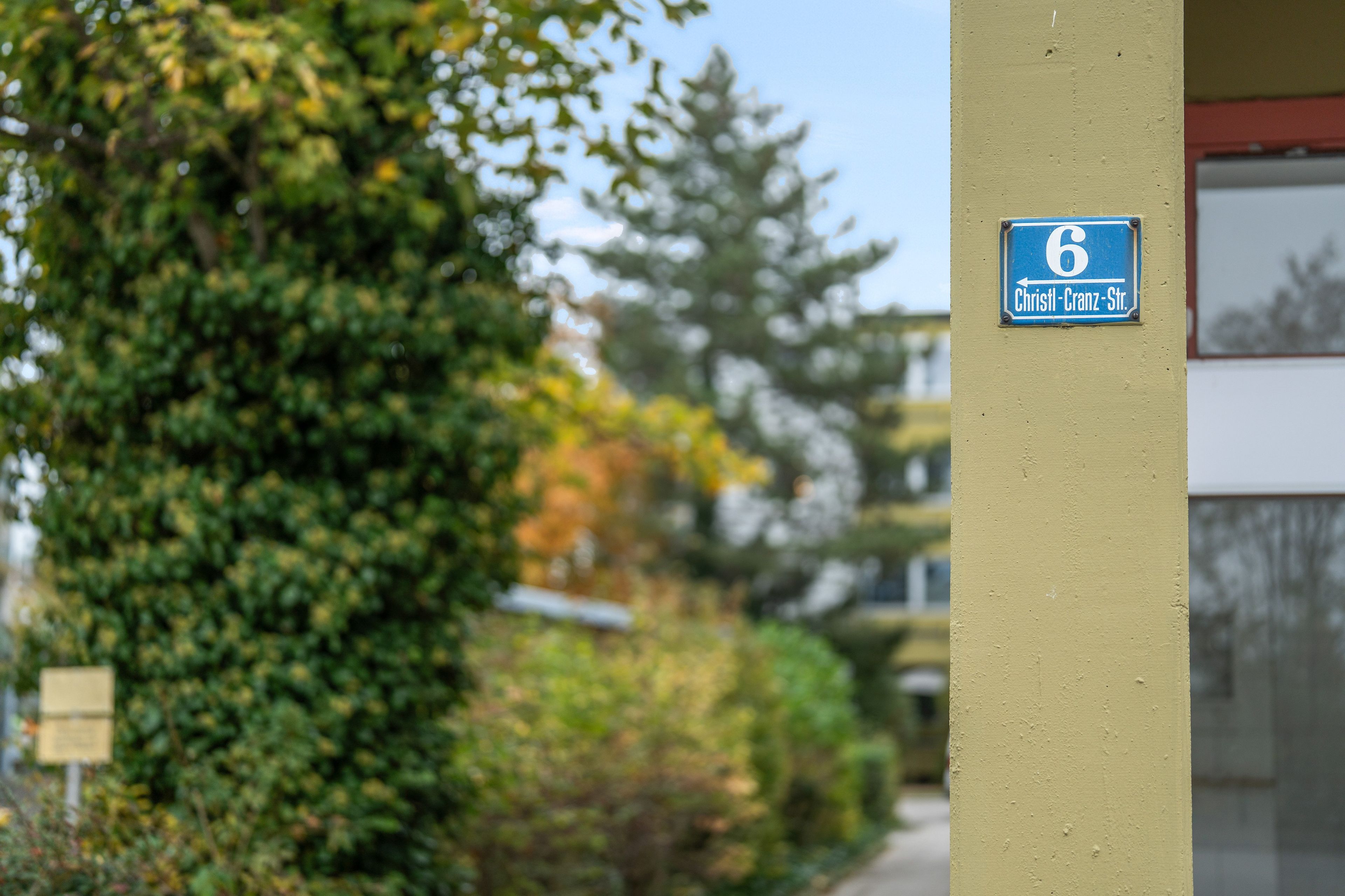 Eine Gebäudeecke mit einem blauen Schild, das '6 Christl-Cranz-Str.' anzeigt.