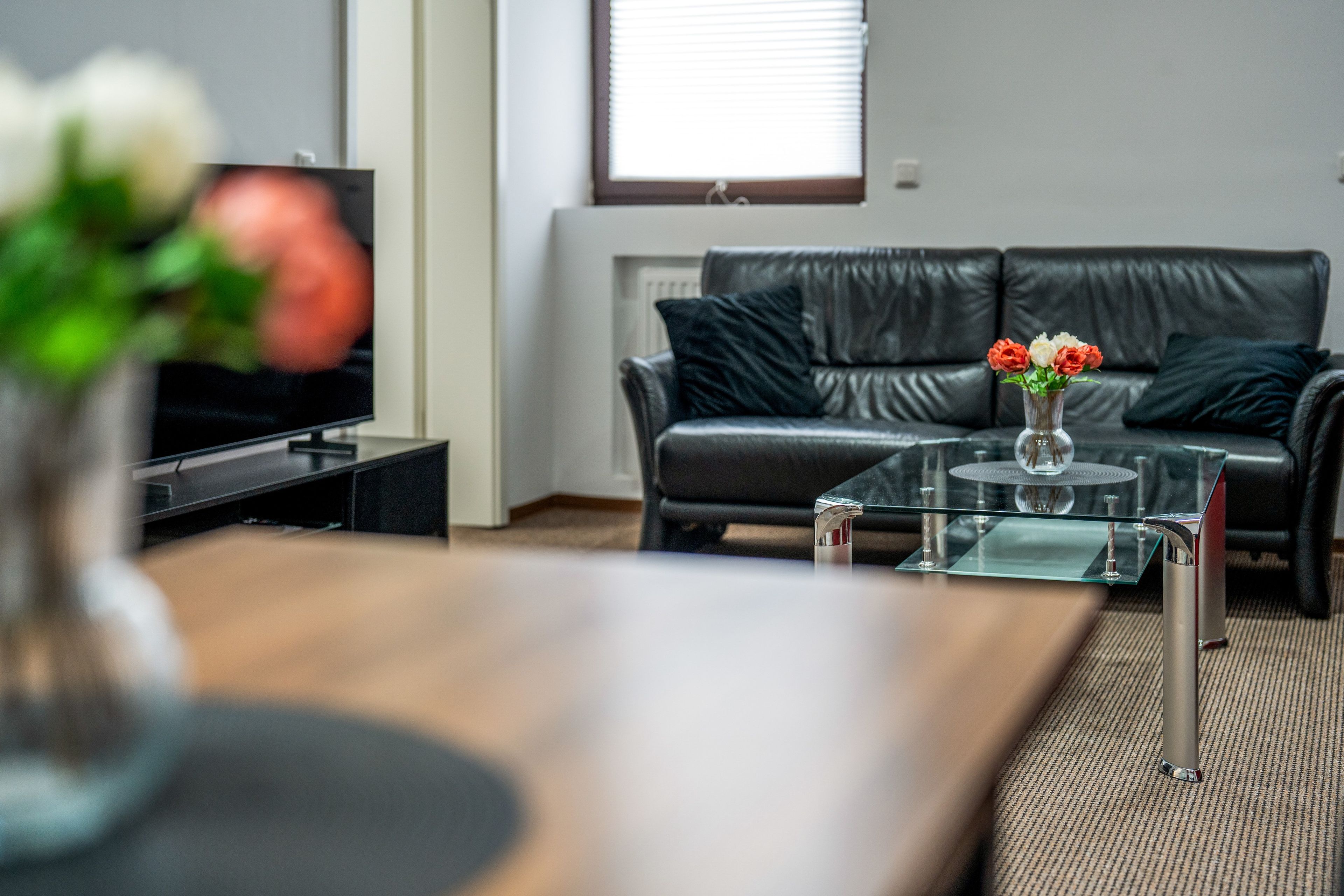 Ein modernes Wohnzimmer mit einer Ledersofa, einem Glastisch und einem Flachbildfernseher.