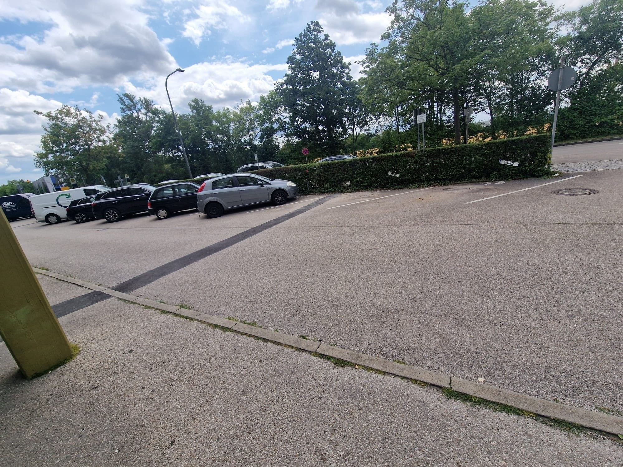 A parking lot with several cars and a white van.