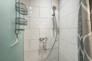 A shower with a handheld showerhead and a wall-mounted faucet.