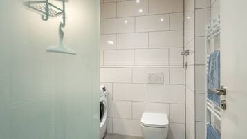 A modern bathroom with a toilet, washing machine, and a towel rack.