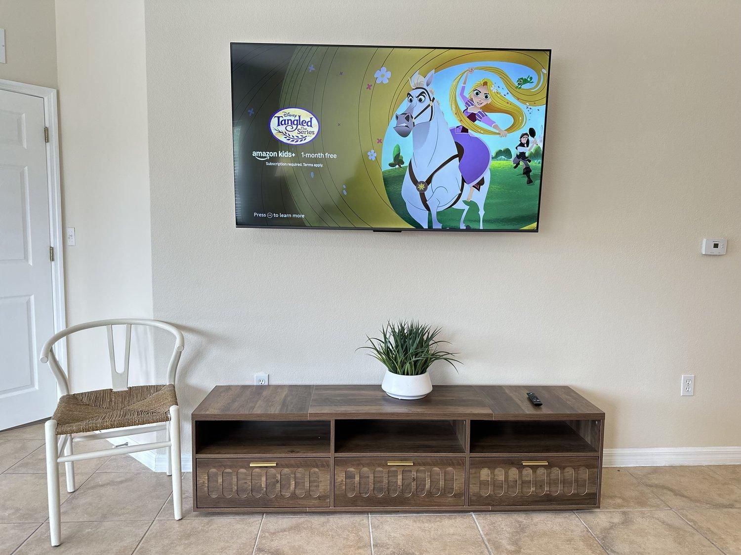 Ein flachbildfernseher an der Wand mit einer Werbung für die Disney-Serie Tangled.