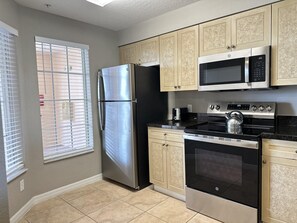 A kitchen with a stainless steel refrigerator, a microwave, an oven, and a stove. - 1406 Spacious 2/2 Resort Condo Near Disney (Orlando)