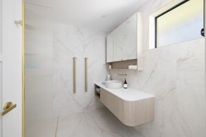 A modern bathroom with a marble floor, a built-in sink, and a large mirror above the vanity.