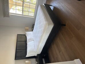 A room with a bed, a window with blinds, a bedside table, and a lamp. - 1506 Luxurious 2/2 Resort Condo Near Disney (Orlando)