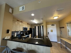 A kitchen with a central island, built-in appliances, and a dining area with a bench. - 2403 Spacious 2/2 Resort Condo Near Disney (Orlando)
