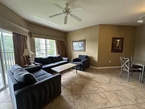 A spacious living room with a large sofa set, a coffee table, and a dining area with chairs. - 3203 Spacious 2/2 Resort Condo Near Disney (Orlando)