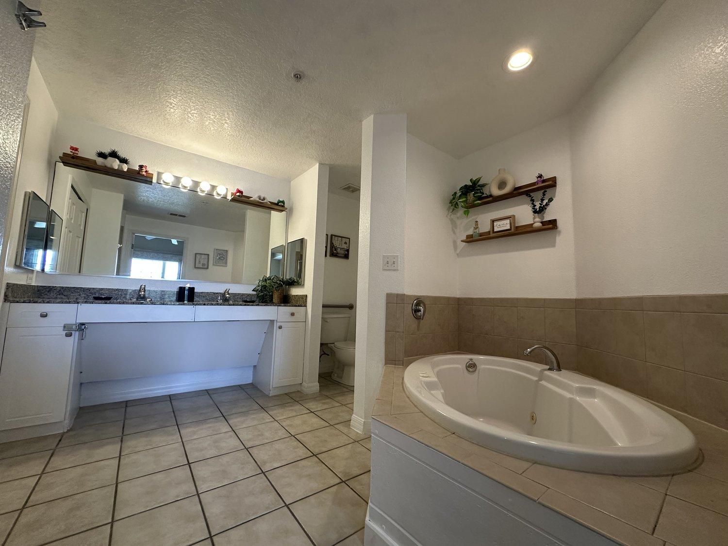 A bathroom with a large bathtub, a sink, and a mirror.