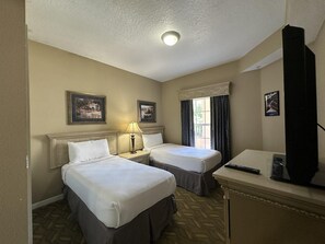 A hotel room with two beds, a desk with a television, and a window with curtains. - 3206 Spacious 2/2 Resort Condo Near Disney (Orlando)