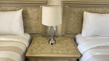 Une chambre d’hôtel avec deux lits, une table de chevet avec une lampe et un tableau encadré au-dessus de chaque lit.