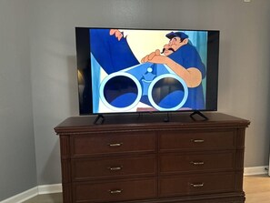 Ein Flachbildfernseher auf einer hölzernen Kommode vor einer Wand.