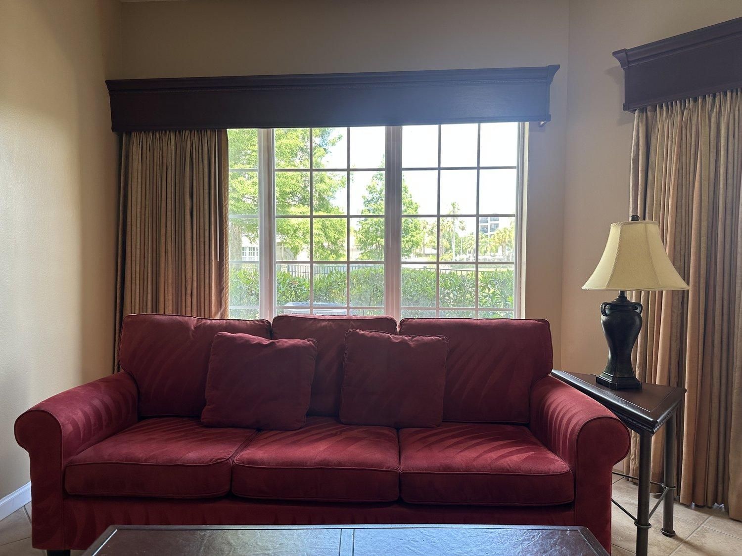 A room with a red sofa, a table, and a lamp.