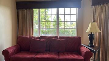 A room with a red sofa, a table, and a lamp.