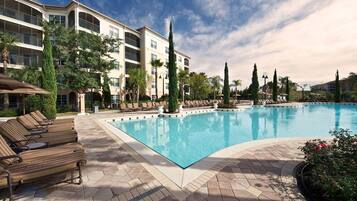 Une piscine avec des chaises longues et, au fond, un bâtiment doté de balcons.