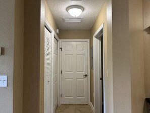 A hallway with a white door, a ceiling vent, and a light fixture. - 4106 Spacious 2/2 Resort Condo Near Disney (Orlando)