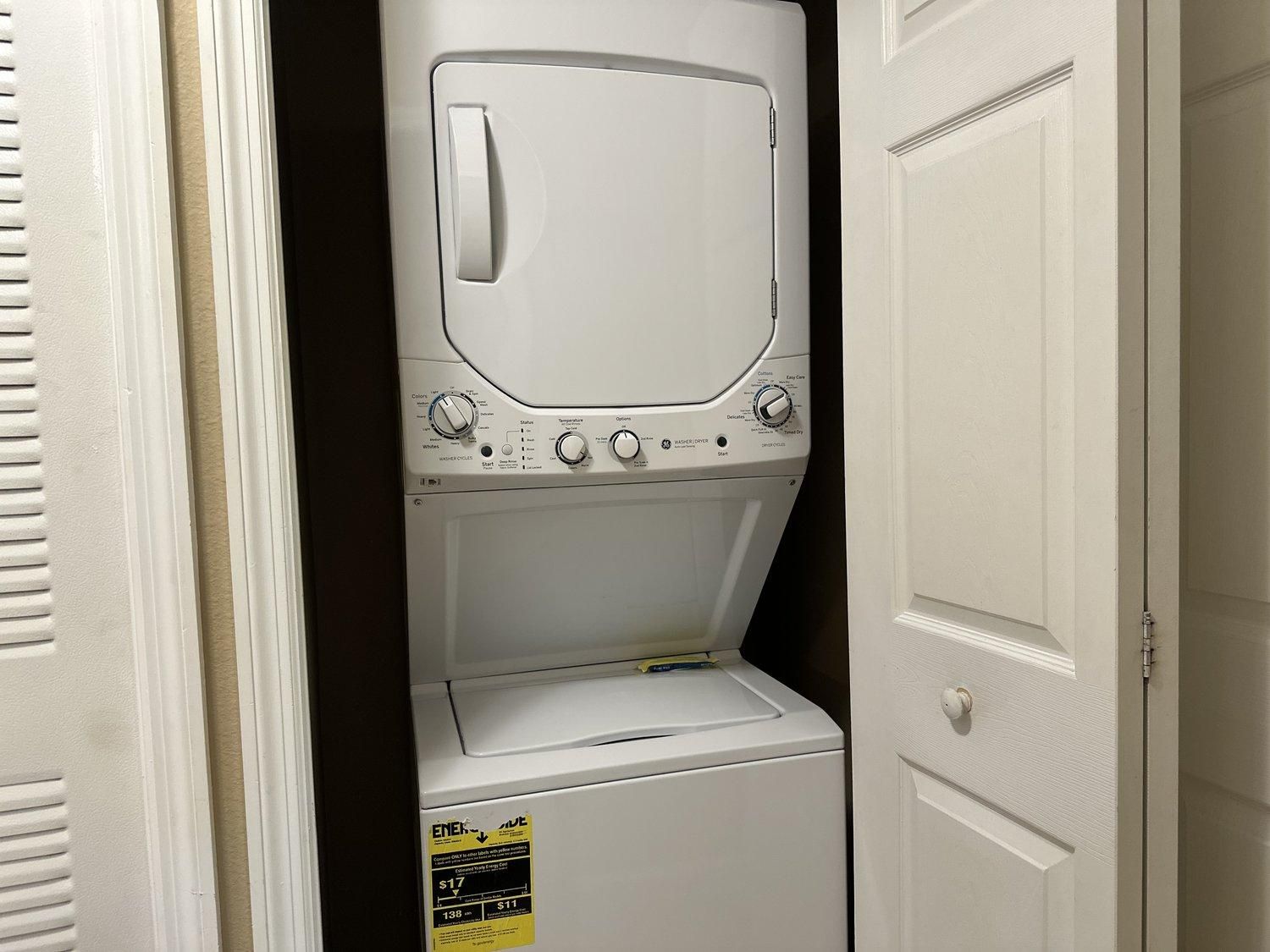 Vue de face d’une buanderie avec une machine à laver et un sèche-linge superposés.
