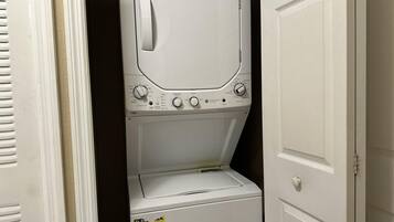 Vue de face d’une buanderie avec une machine à laver et un sèche-linge superposés.