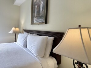 A neatly made bed with white linens and pillows, a dark wooden headboard, and a framed picture on the wall. - 4306 Spacious 2/2 Resort Condo Near Disney (Orlando)