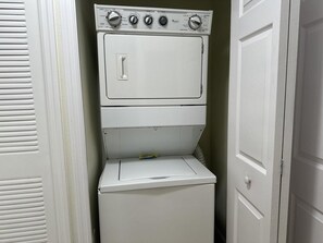 A compact laundry room with a front-loading washer and dryer stacked vertically.