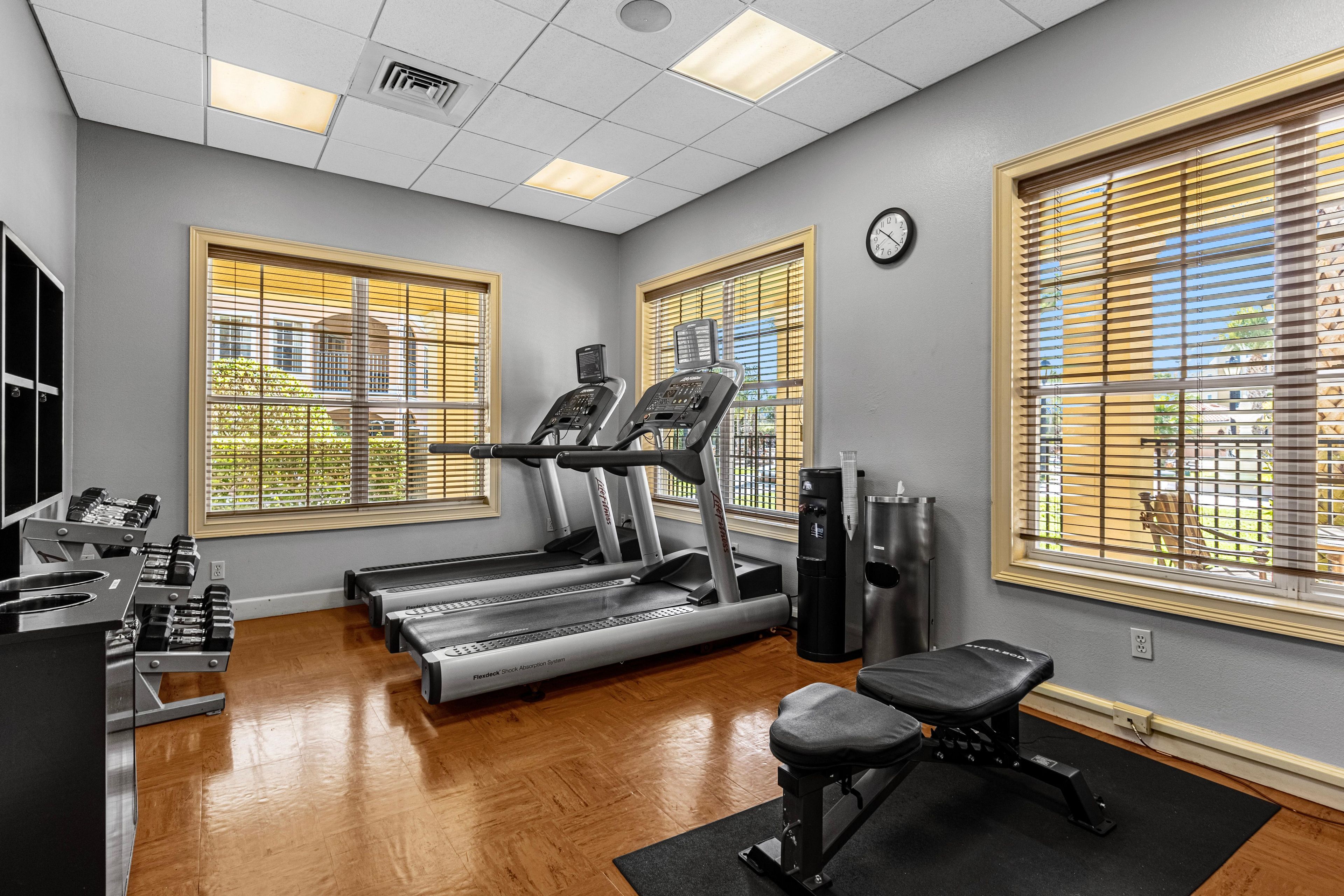 Une salle de sport équipée de tapis de course, de poids et d’un banc.
