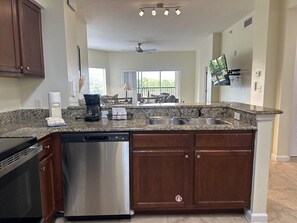 A kitchen with granite countertops, stainless steel appliances, and wooden cabinets. - 4306 Spacious 2/2 Resort Condo Near Disney (Orlando)