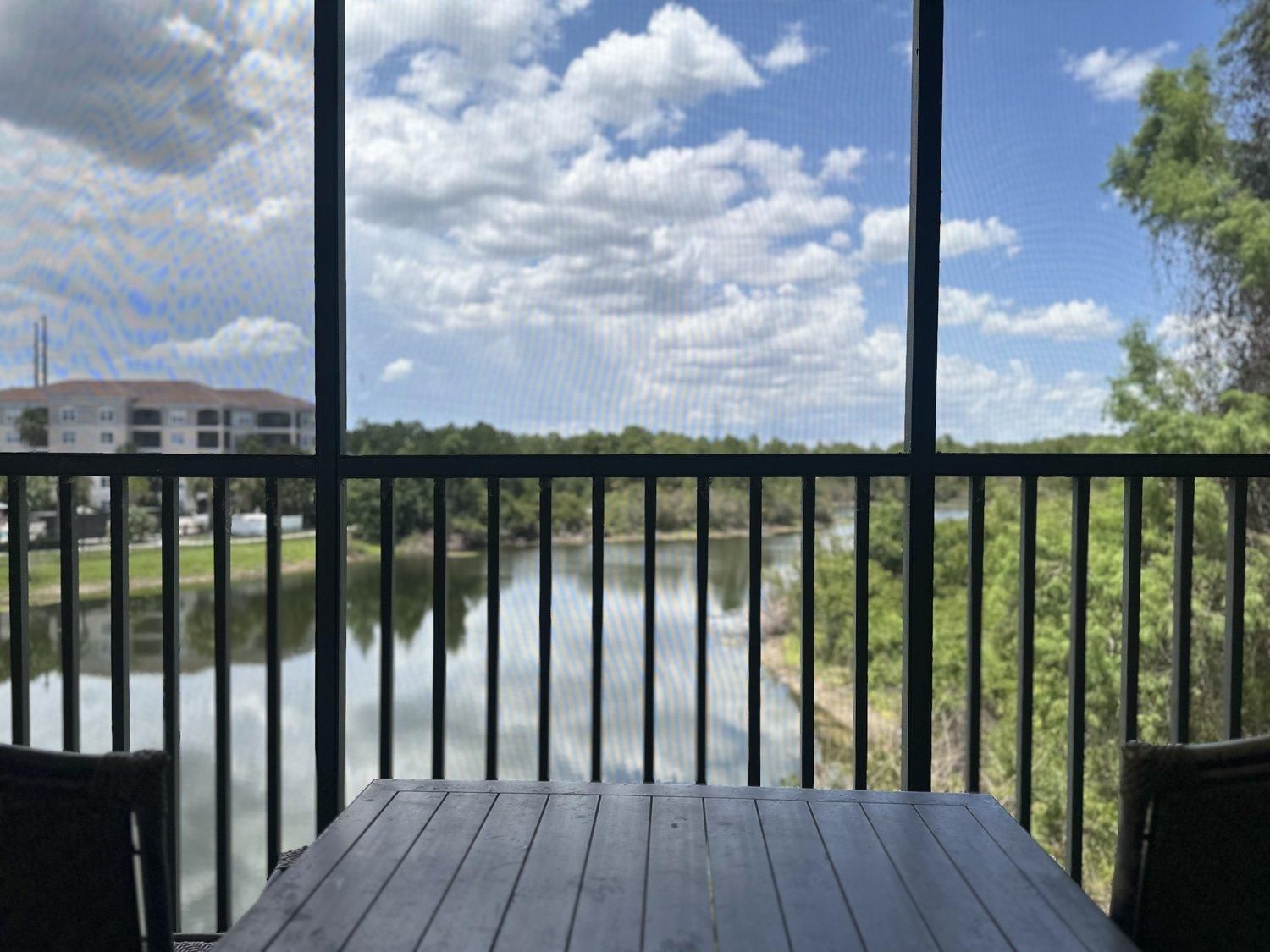 A wooden deck with a view of a calm river and a building across the water.